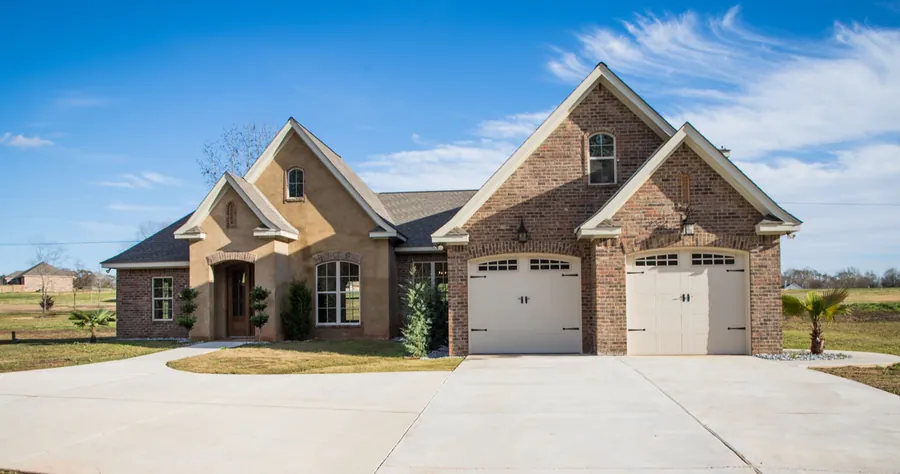 Brick custom home with gabled rooflines, arched windows and two carriage-style garage doors