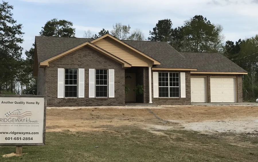 Brick ranch home with a two-car garage and a Ridgeway Homes yard sign out front