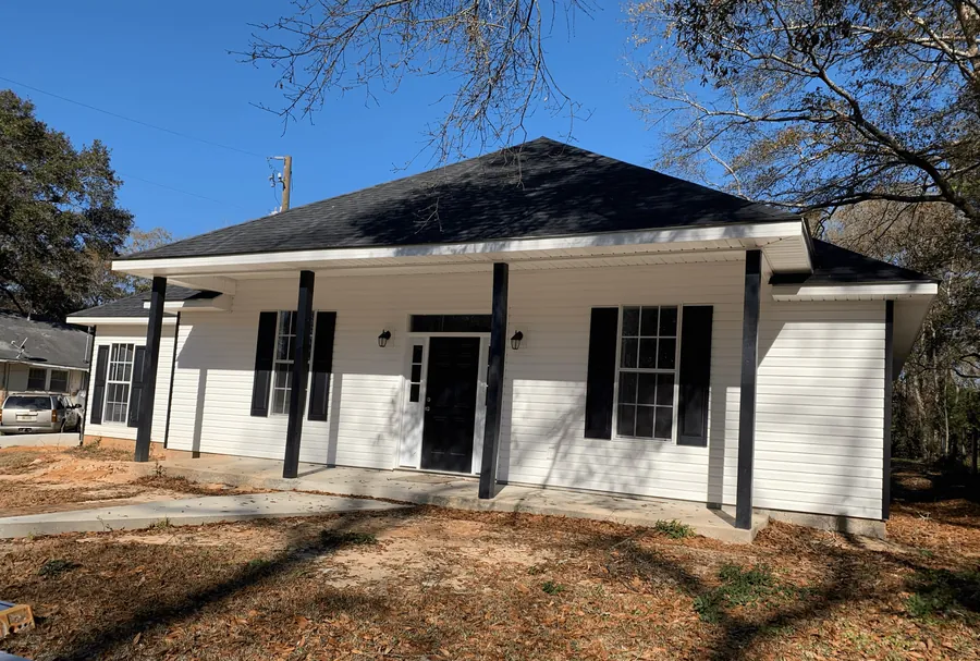 White-sided home with black shutters and a full-width front porch on dark columns