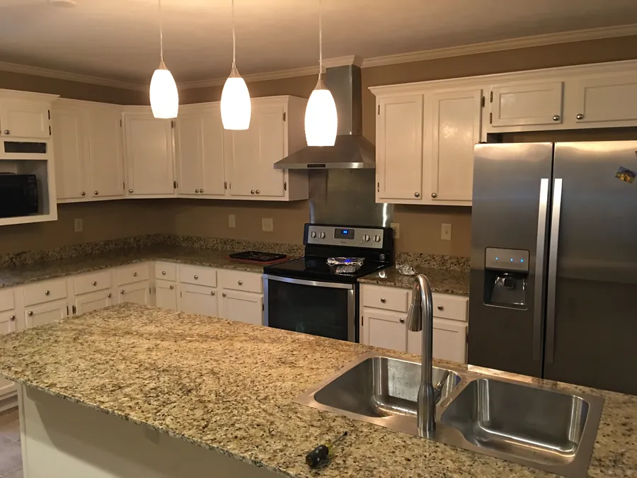 Renovated kitchen with white cabinets, granite counters, pendant lights and stainless appliances